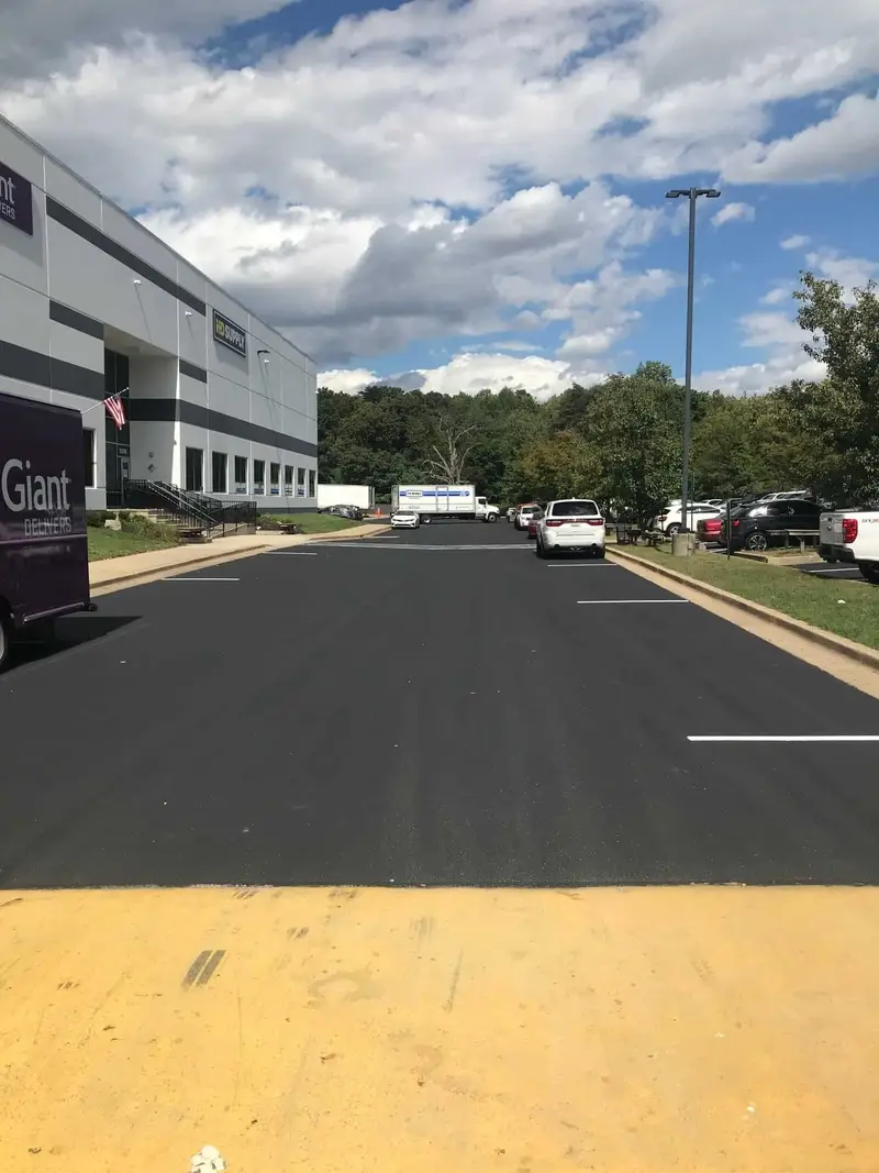 Newly sealcoated parking lot beside a large warehouse