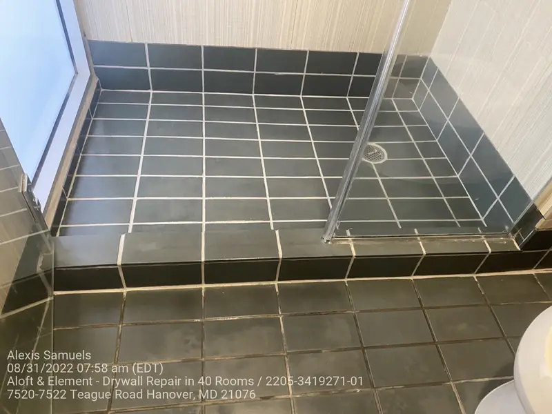 Hotel shower with dark tile and newly replaced grout