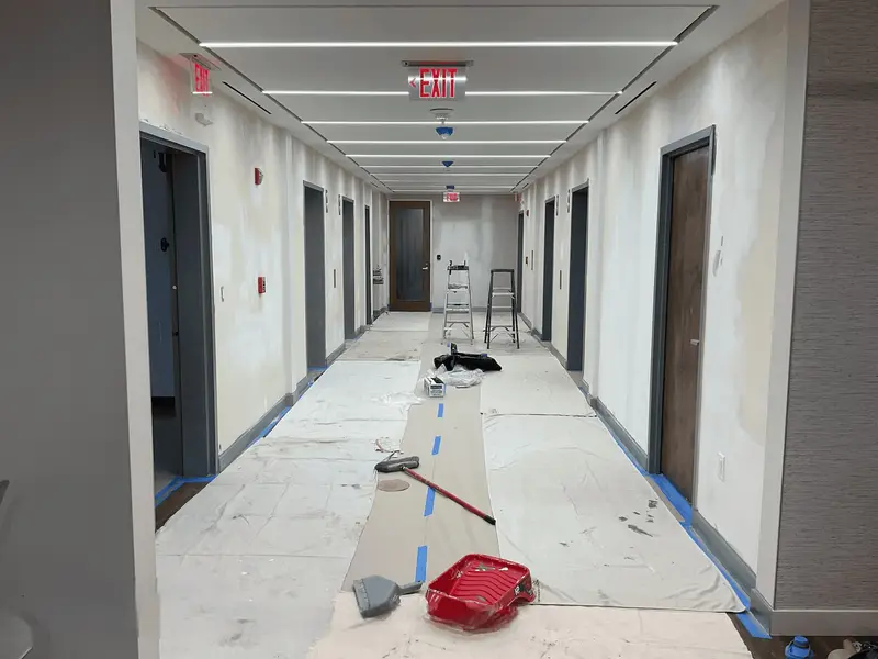 Corridor renovation in progress with drop cloths, ladder, and new interior doors