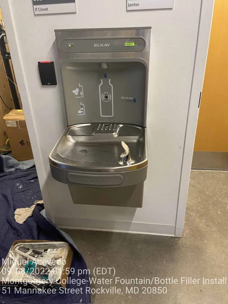 Wall-mounted water fountain with bottle filler installed in a college gym