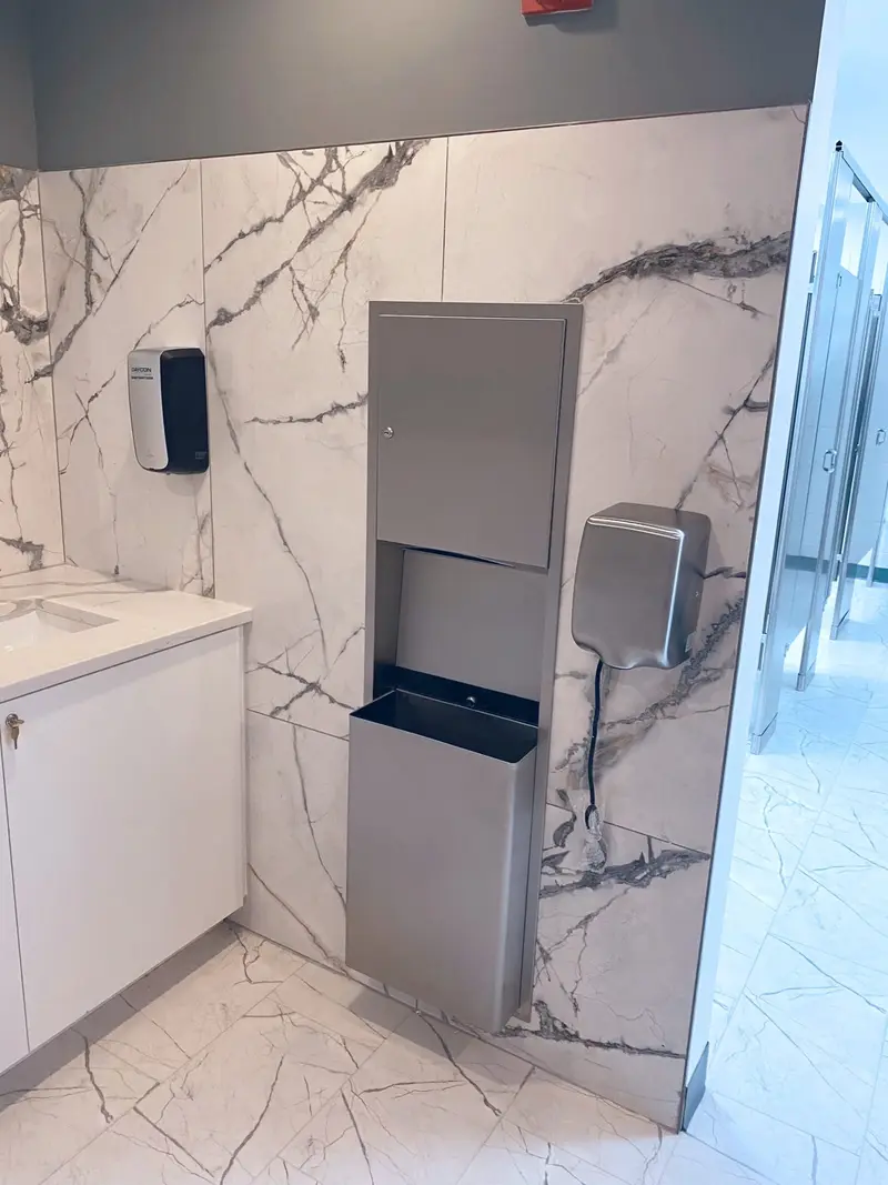 Renovated commercial restroom with marble-look walls and stainless fixtures