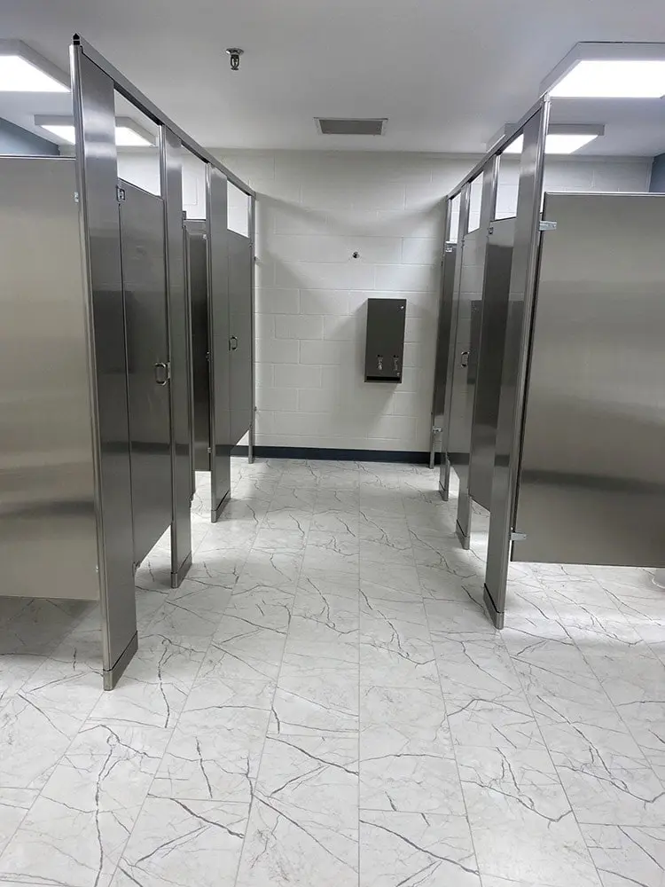 Commercial restroom with six stalls and a new white tile floor