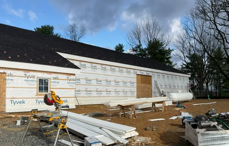 New commercial building wrapped in house wrap with a new shingle roof, trim being installed