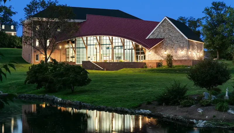 Stone and glass school fine arts center with red roof at dusk