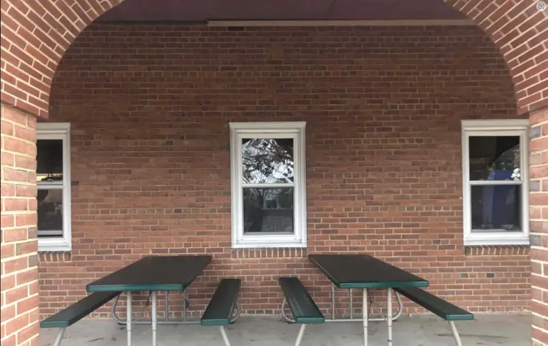 Brick school courtyard with new windows and picnic tables under an archway